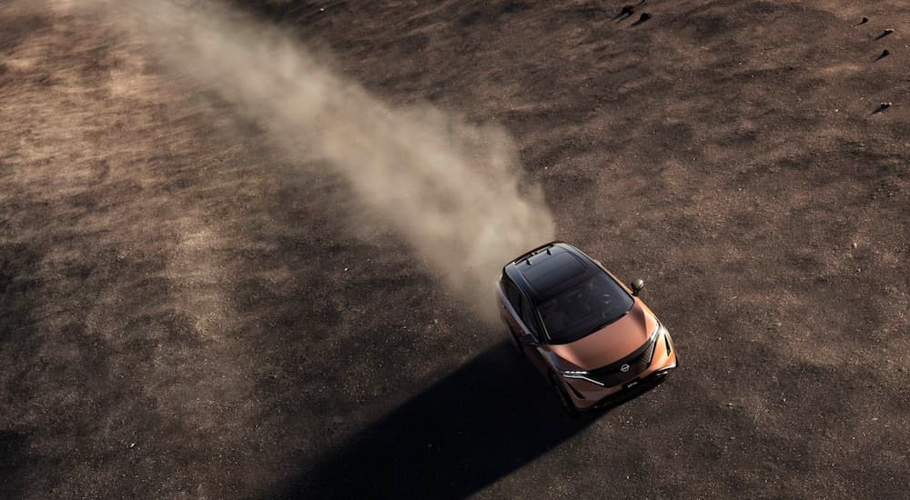 One of the most popular Nissan SUVs, a copper and black 2022 Nissan Ariya, is shown driving off-road.