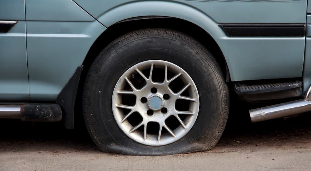 A blue vehicle is shown with a flat tire.