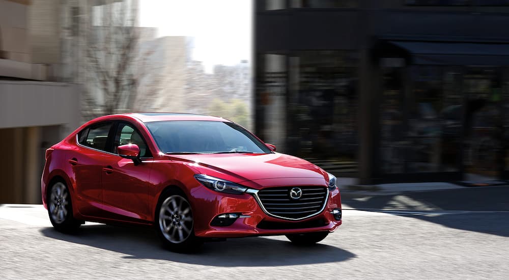 A red 2018 Mazda 3 sedan is shown parked after visiting a used car sales dealership.
