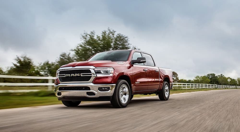 A red 2020 Ram 1500 is shown driving on a road.