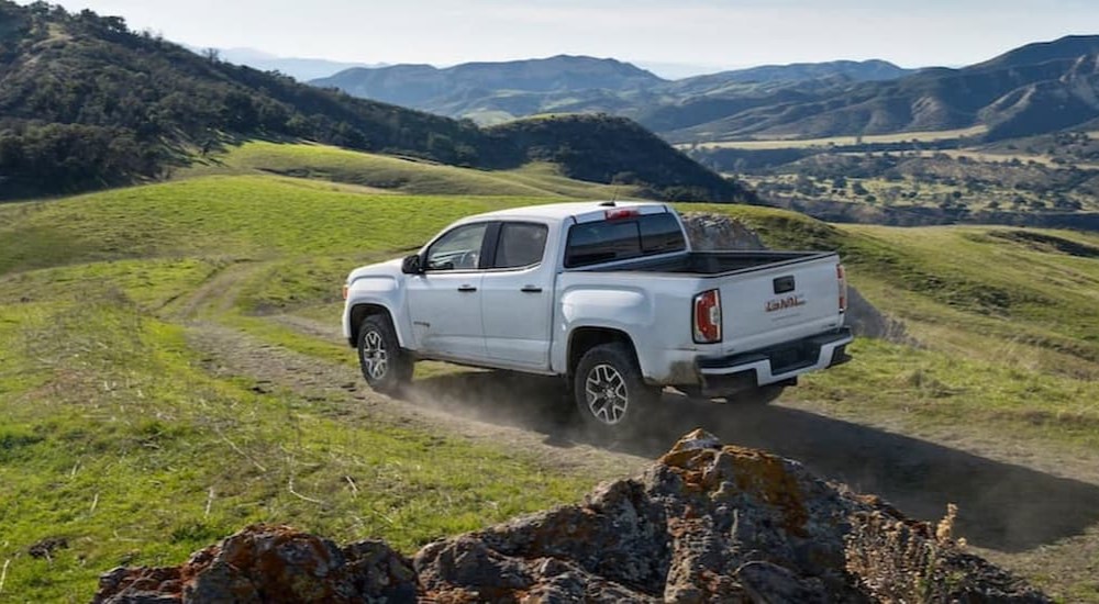 A white 2021 GMC Canyon is shown driving off-road.