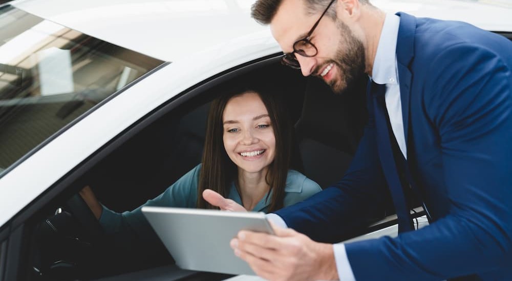 A customer and salesperson are shown looking at a tablet as they 'value my trade.'