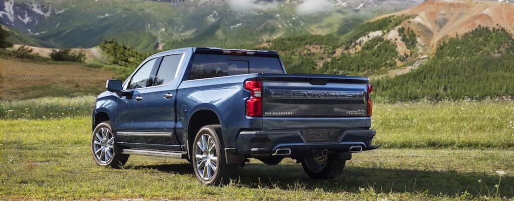 A blue 2024 Chevy Silverado High Country is shown from the rear at an angle.