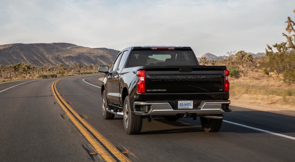 A black 2022 Chevy Silverado 1500 LT is shown from the rear at an angle after leaving a dealer that has a Chevy Silverado for sale.