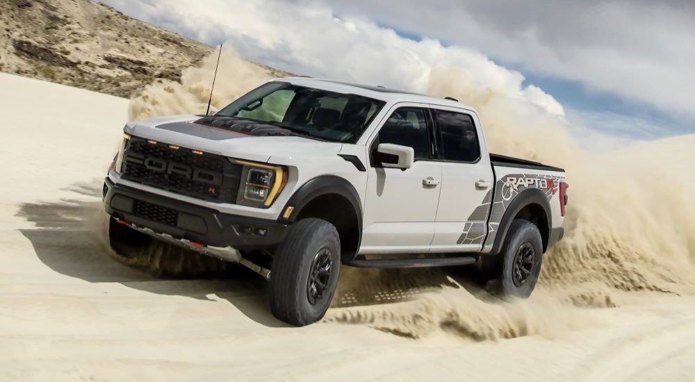 A popular Ford F-150 for sale, a light grey 2023 Ford F-150 Raptor R, is shown kicking up dust.