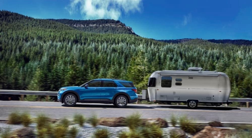 A blue 2023 Ford Explorer is shown towing a trailer.