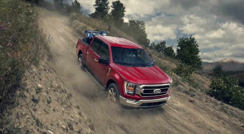 A red 2023 Ford F-150 is shown descending down a hill.