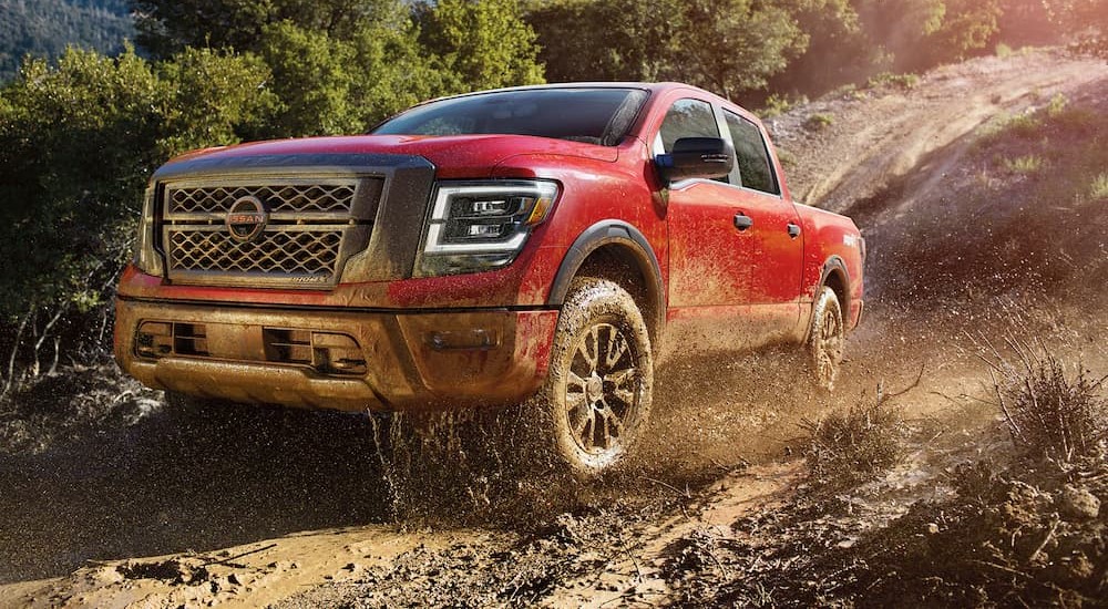 A red 2023 Nissan Titan Pro-4X is shown driving off-road.