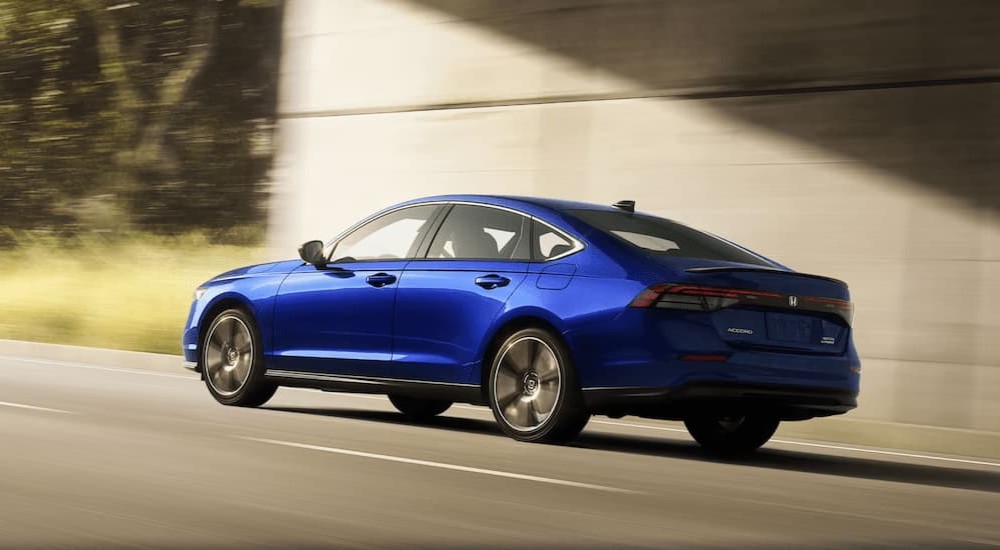 A blue 2023 Honda Accord Sport Touring is shown driving on a highway.