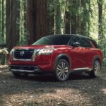 A red 2023 Nissan Pathfinder is shown parked off-road after winning a 2023 Nissan Pathfinder vs 2023 Toyota Highlander comparison.