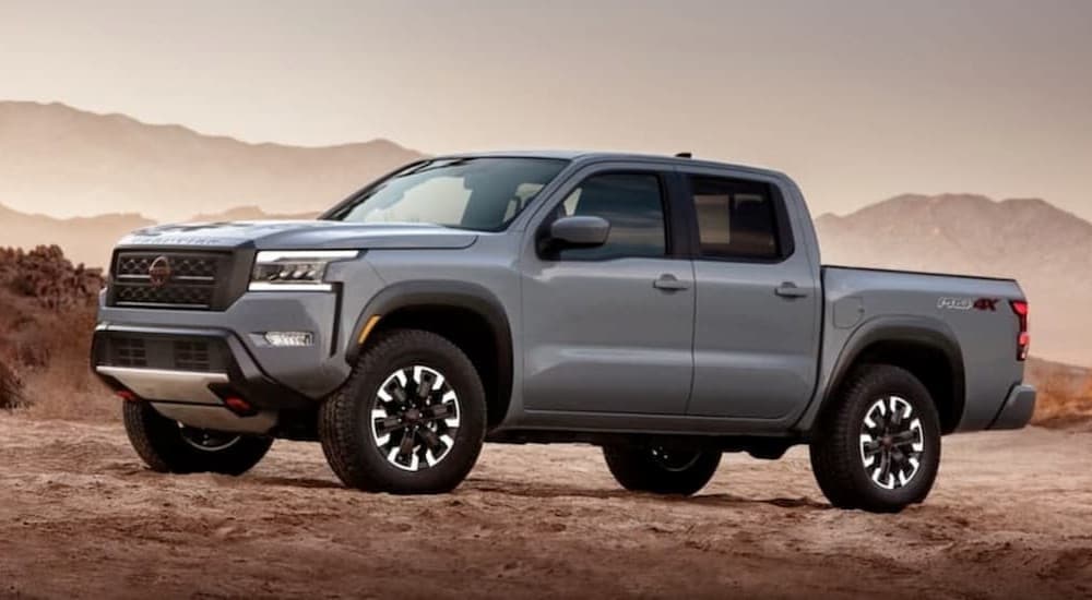 A silver 2023 Nissan Frontier is shown parked on dirt.