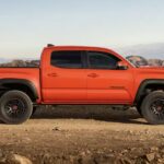 An orange 2023 Toyota Tacoma TRD is shown parked off-road after winning a 2023 Toyota Tacoma vs 2023 Nissan Frontier comparison.