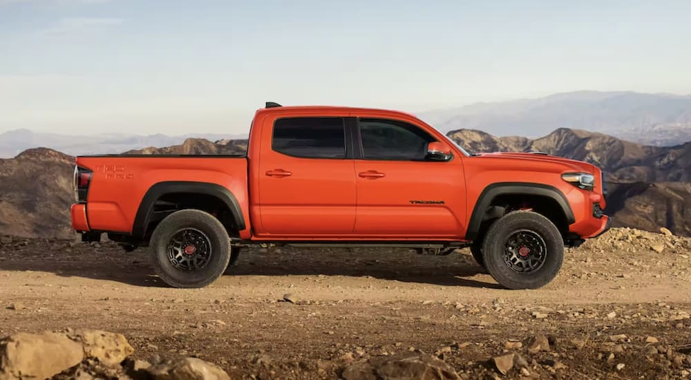 An orange 2023 Toyota Tacoma TRD is shown parked off-road after winning a 2023 Toyota Tacoma vs 2023 Nissan Frontier comparison.