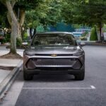 A grey 2024 Chevy Equinox EV 1LT is shown parked on a city street.