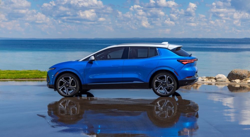 A blue 2024 Chevy Equinox EV 3LT is shown parked in front of the ocean.