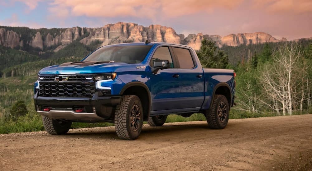 A blue 2024 Chevy Silverado 1500 ZR2 is shown parked near a ridgeline.