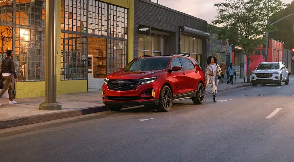 A red 2024 Chevy Equinox RS is shown parked on a city street.
