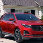 A red 2024 Chevy Equinox RS is shown parked near a house.