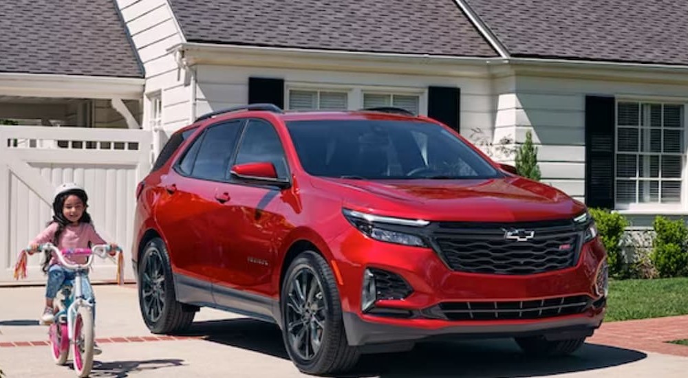 A red 2024 Chevy Equinox RS is shown parked near a house.