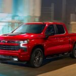 A red 2023 Chevy Silverado 1500 RST is shown driving on a street after visiting a Chevy Silverado dealer.