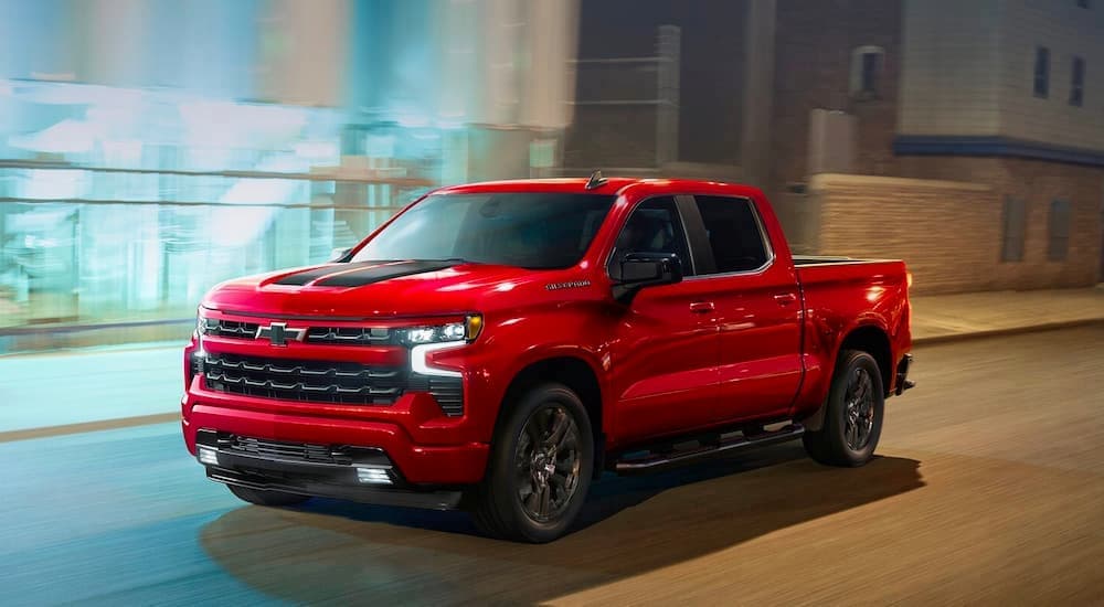 A red 2023 Chevy Silverado 1500 RST is shown driving on a street after visiting a Chevy Silverado dealer.