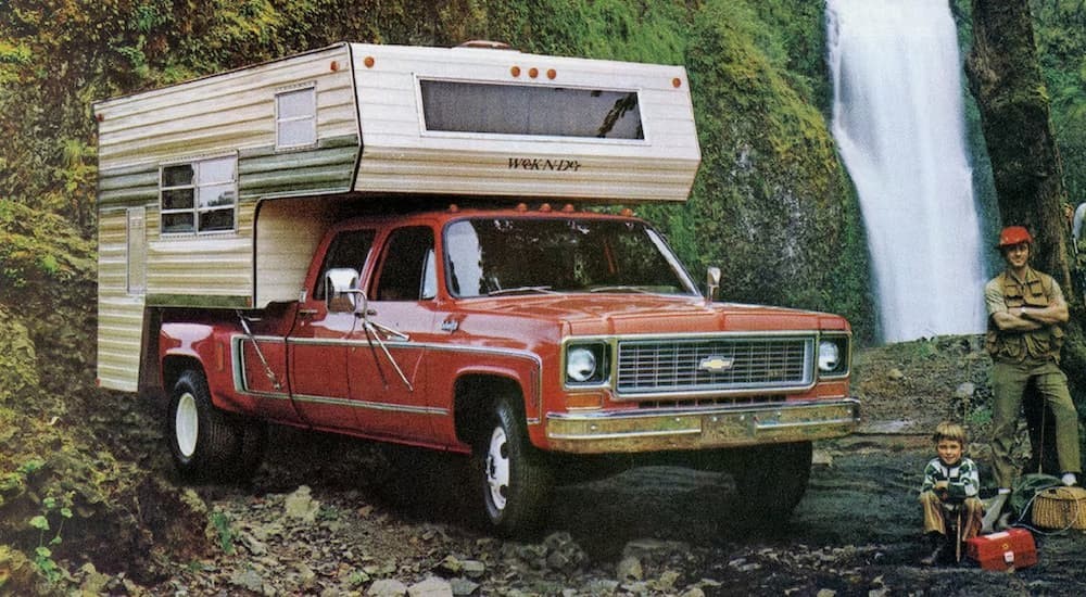 A red 1973 C/K truck is shown parked near a waterfall after visiting a Chevy Silverado for sale.