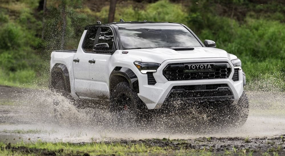 A white 2024 Toyota Tacome is shown driving off-road.