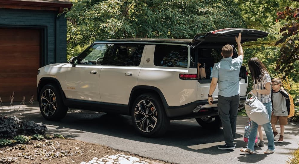 A white 2023 Rivian R1S is shown parked on a driveway.