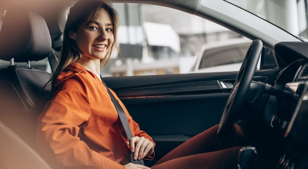 A person in a car is shown buckling their seatbelt.