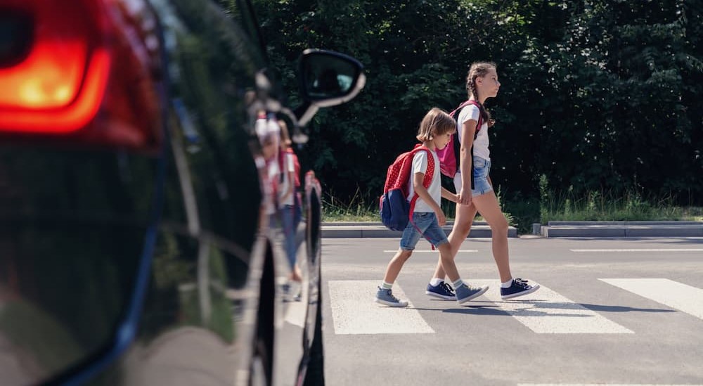 Two children are shown crossing a road on a crosswalk.