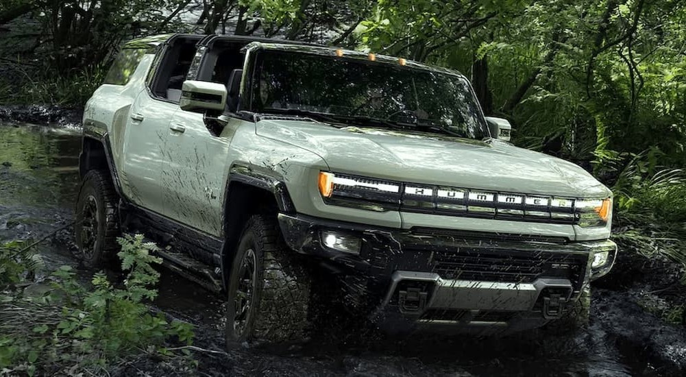 A green 2024 GMC Hummer EV is shown off-roading.