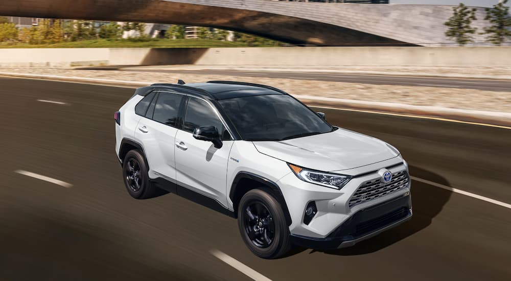 A white 2020 Toyota RAV4 is shown driving on a highway.