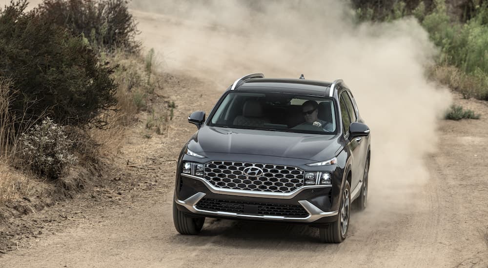 A grey 2022 Hyundai Santa Fe is shown from the front while driving on a dirt trail.