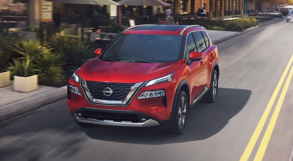 A popular Nissan Rogue for sale, a red 2023 Nissan Rogue, is shown driving on a city street.