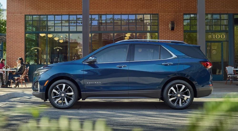 A blue 2023 Chevy Equinox is shown parked near a restaurant.