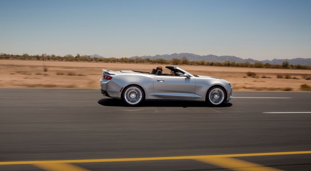 A silver 2018 Chevy Camaro SS is shown from the side on an open road.