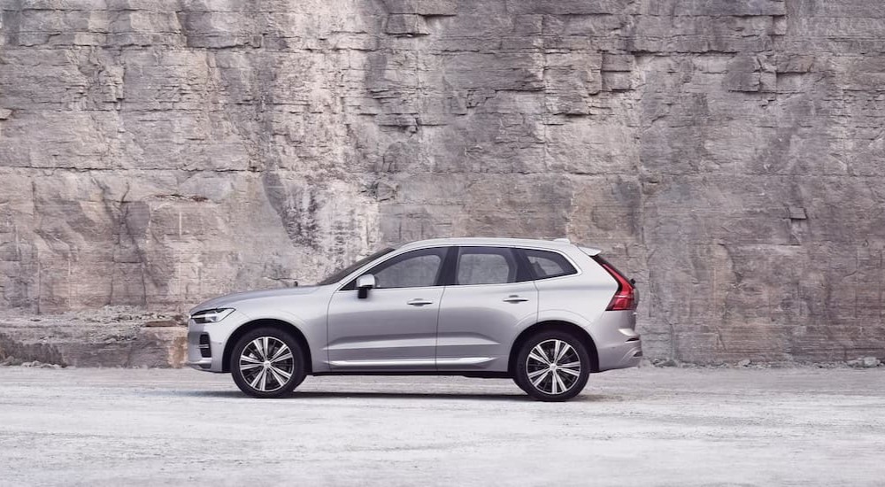 Purchased by Volvo-Dan, a silver 2023 Volvo XC60, is shown parked near a stone wall.