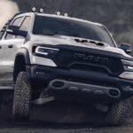 A white 2023 Ram 1500 TRX is shown off-roading on dirt.