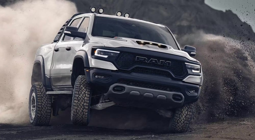 A white 2023 Ram 1500 TRX is shown off-roading on dirt.