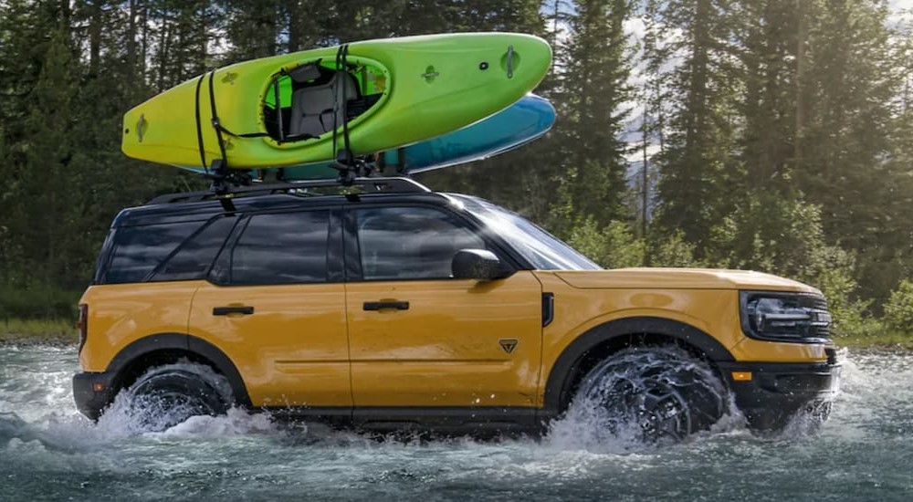 A popular used 2021 Ford Bronco Sport for sale, a yellow 2021 Ford Bronco Sport, is shown driving off-road.