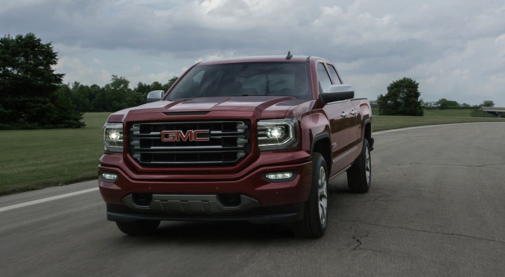 A red 2016 GMC Sierra 1500 is shown driving on a road.