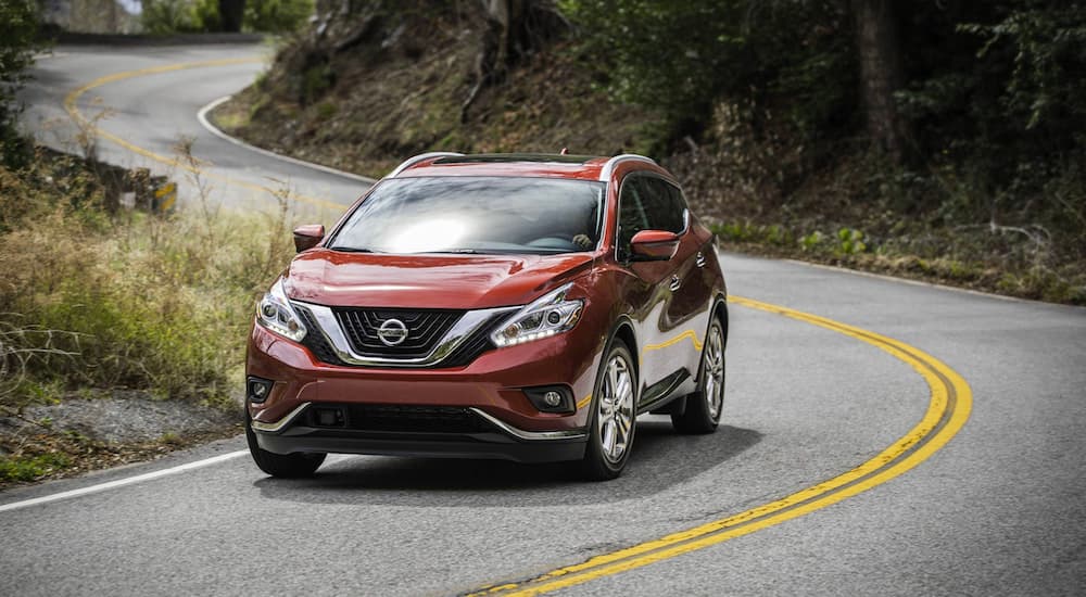 A red 2018 Nissan Murano is shown driving on a highway.