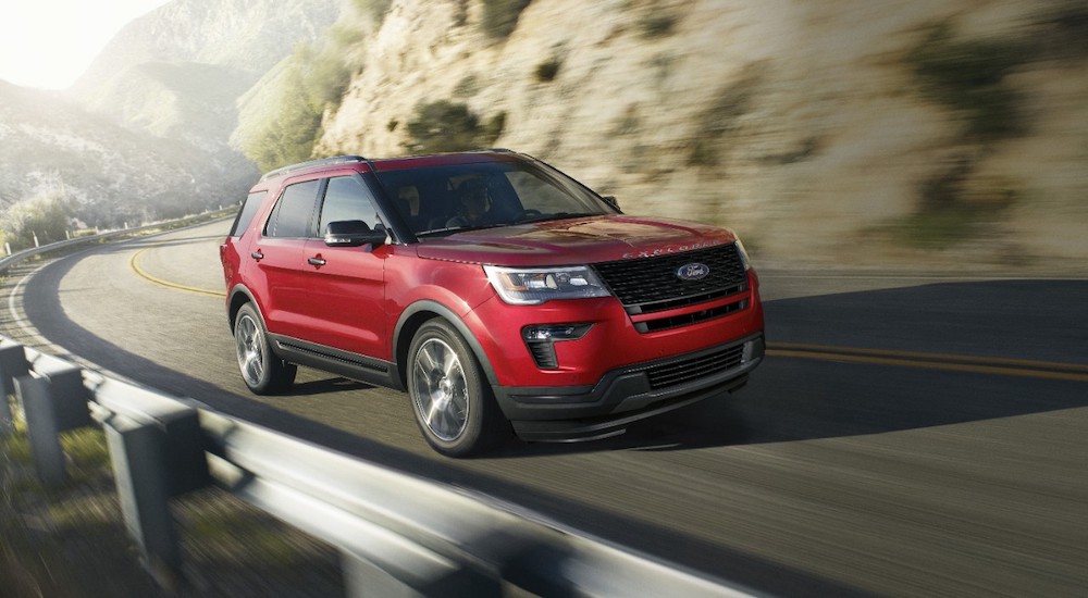 A red 2019 Ford Explorer is shown driving on a highway after visiting a used car dealer.