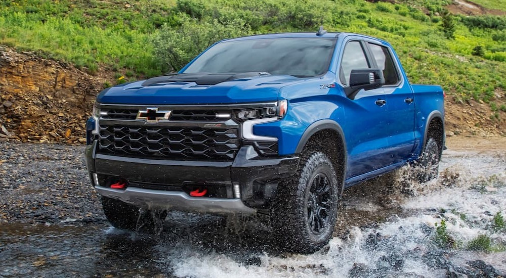 A popular truck for sale, a blue 2022 Chevy Silverado 1500 ZR2, is shown driving off-road.