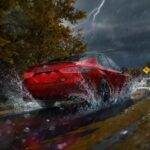 A red 2023 Toyota Camry is shown driving on a wet road near lightning.