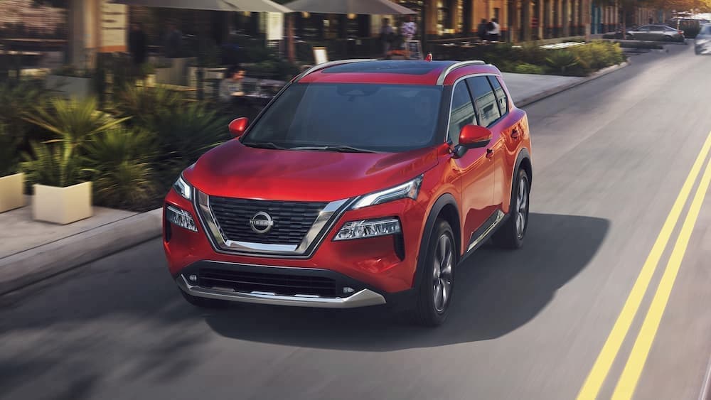 A red 2023 Nissan Rogue is shown driving on a street.