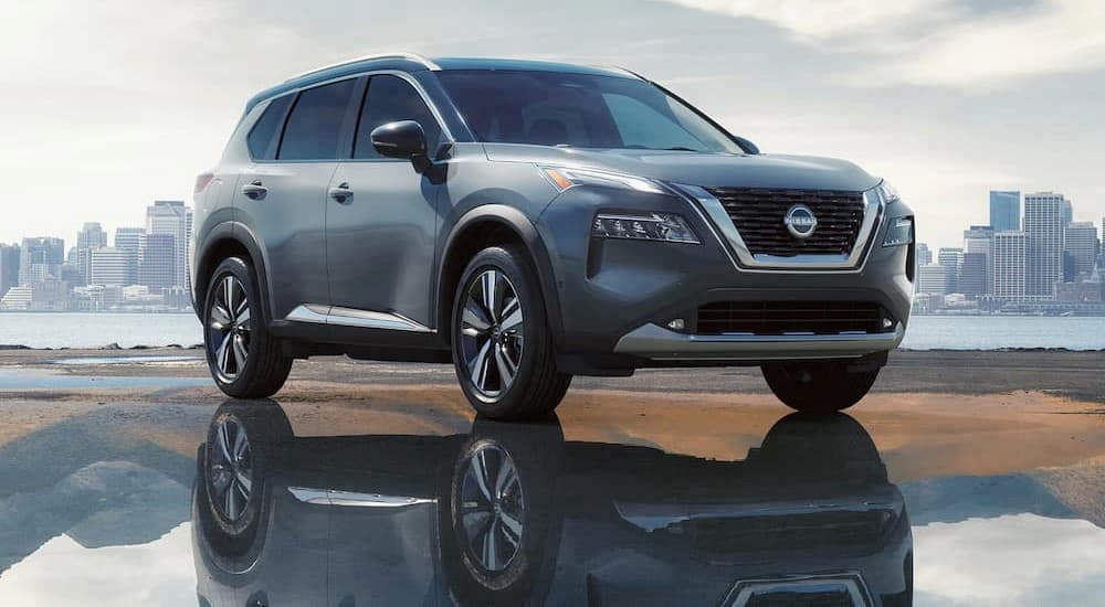 A silver 2023 Nissan Rogue SV is shown parked on a puddle near a lake.