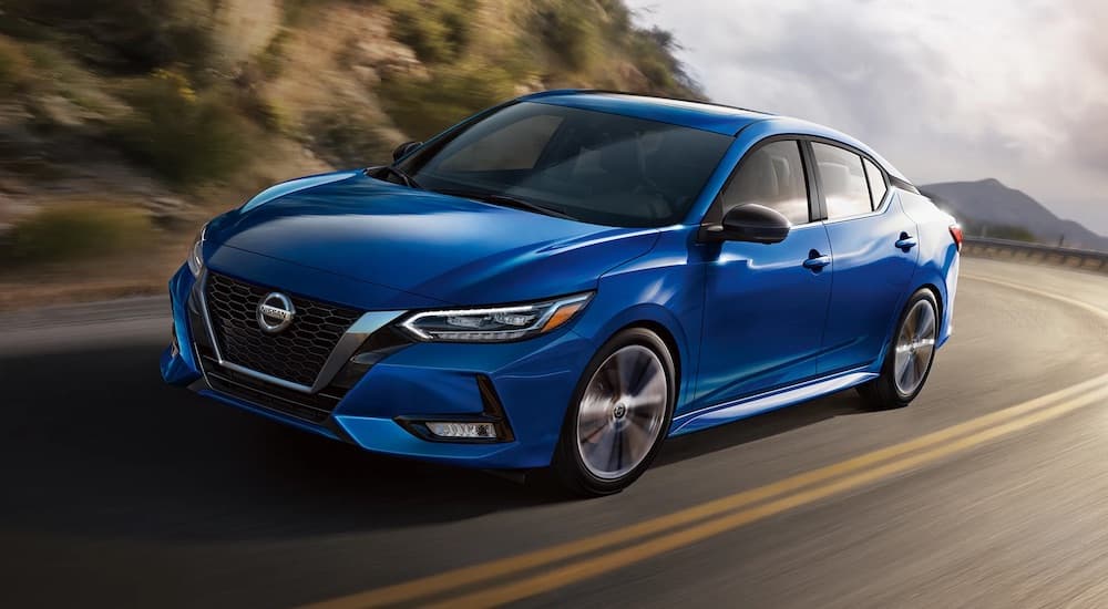 A blue 2023 Nissan Sentra is shown from the front at an angle during a 2023 Nissan Sentra vs 2023 Honda Civic comparison.