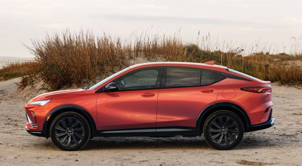 An orange 2024 Buick Envista ST is shown from the side on beach sand.