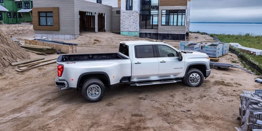 A white 2024 Chevy Silverado 3500HD High Country is shown parked on a construction site.